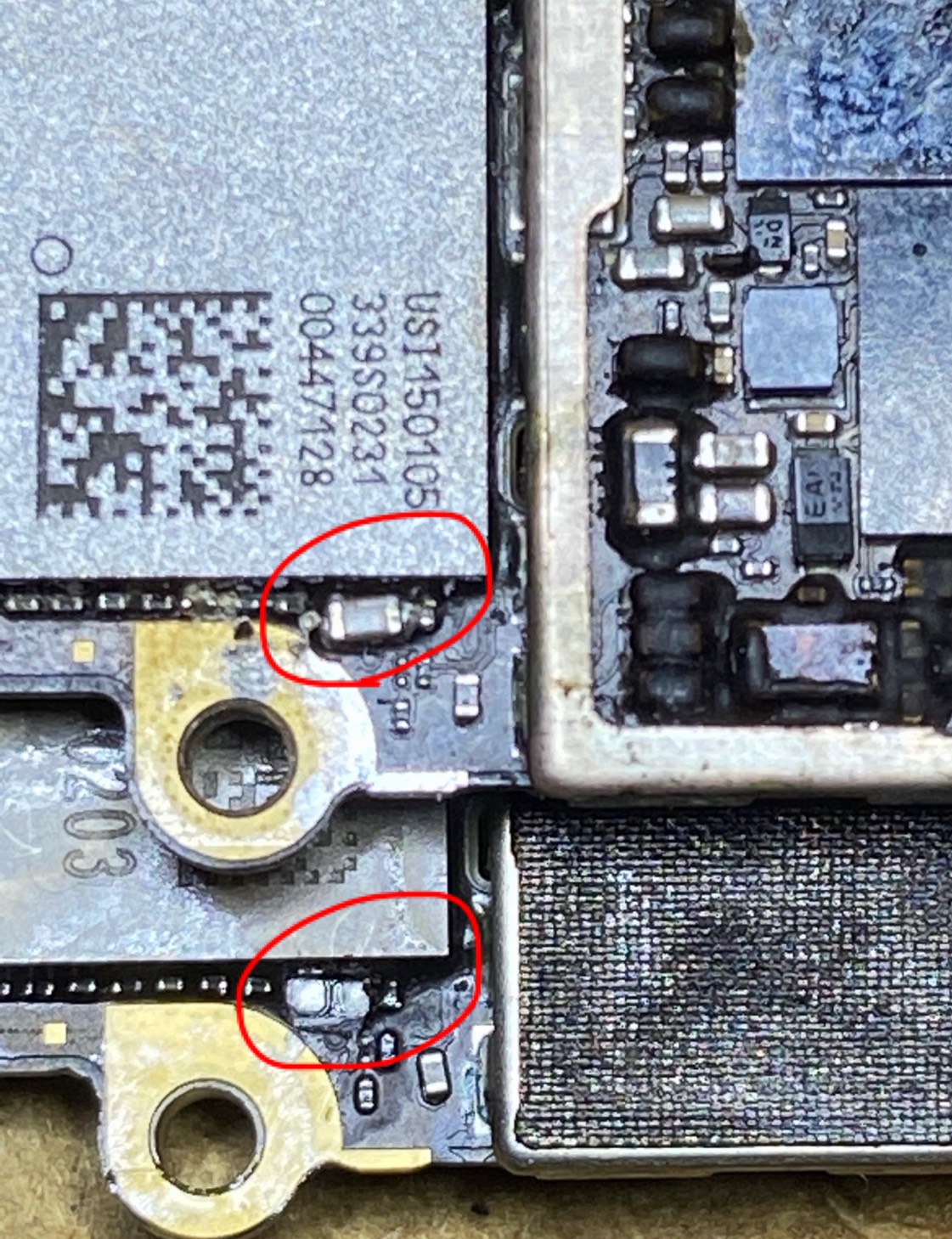 顕微鏡でiPhoneの基板を拡大し、故障している部品を赤丸で特定している診断写真