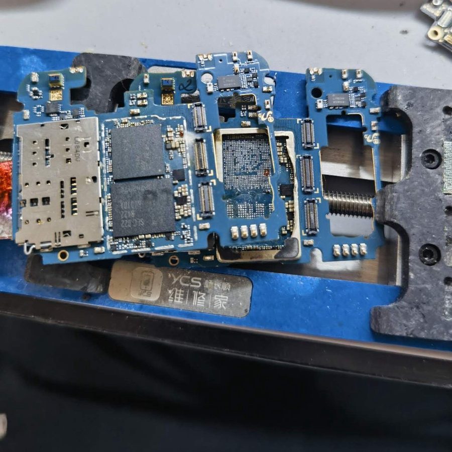スマートフォンの基板を治具に固定して基板修理を行っている作業写真
